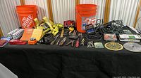 Full overview of the tool collection including two orange Home Depot buckets, various hand tools, saw blades, and other accessories spread out on a black cloth