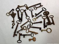 Overhead view of all 25 brass keys laid out on white surface