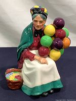 Front view of Royal Doulton porcelain figurine with woman holding colorful balloons next to flower basket