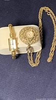 Two watches on white jewelry pillow: Bulova wristwatch and Sovereign pendant watch on chain