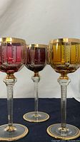 Three colored goblet glasses side by side showing full set