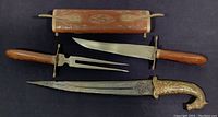 Full set displayed on black background showing carving knife, fork, scabbard holder, and decorative dagger.