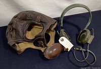 Pilot cap and headset shown side by side on dark surface for size and condition overview.