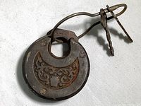 Front view of vintage padlock showing decorative cutout and metal loop holding two keys.