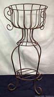 Full view of vintage welded steel wire plant stand showing the entire structure including base and basket top with curled handles.