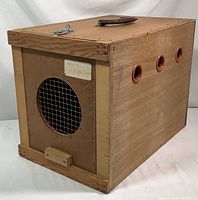 Front-left angle showing wire mesh circular vent and wooden stopper block on front panel, side air holes, and wood grain finish