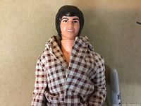 Close-up of doll's face and upper torso showing facial features and checkered shirt.