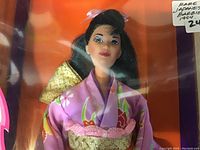 Close-up of the Barbie doll face showing kimono fabric details and facial features through the sealed box plastic.
