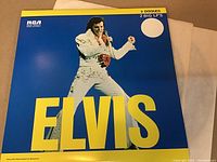Front cover of the Elvis Presley double LP vinyl record showing Elvis performing, blue background, yellow text and RCA label.
