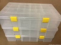 Stack of 3 closed clear plastic Plano storage boxes with yellow latches