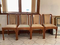 Set of four mid century modern bentwood dining chairs with beige upholstery arranged in a row.