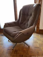 Front-side angle showing the brown corduroy upholstery and chrome swivel base of the lounge chair.