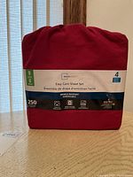 Front packaging showing Mainstays Easy Care Sheet Set in red color with 4 pieces, 250 thread count, wrinkle resistant, cotton rich, machine washable, quick dry icons.