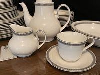 Close-up of teacup and saucer alongside creamer and teapot