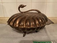 Closed swan serving dish with dark patina side view showing curved neck and small feet.