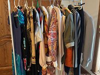 Side view of the full rack of vintage 1980s clothing including dresses and tops with varied colors and patterns around 12 items.