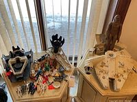 Overview of two large playset components on table by window with large Chewbacca figure standing in Millennium Falcon bottom half and assorted smaller figures and accessories