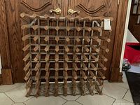 Front view of wood and metal wine rack showing grid bottle holders and metal supports