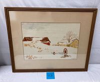 Framed watercolor painting showing wintery countryside barns, a leafless tree, and a wooden wagon wheel in snow.