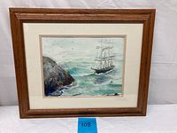 Framed watercolor painting showing a clipper ship sailing near rocky cliffs with birds flying in the sky.