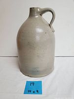 Front view of grey salt glazed crock jug showing bulbous body and handle