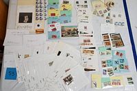 Top view of a large assortment of foreign stamps and postage blocks arranged on a flat surface, including loose stamps, blocks, and sets mounted on cards.