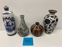 All four pottery items shown side by side, including the Delft bottle and three studio pottery vases in various forms and colors.