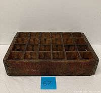 Front and top view of the wooden crate with visible compartments and side advertising text.
