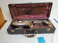Opened case showing saxophone body, detachable neck, mouthpiece, ligature and strap