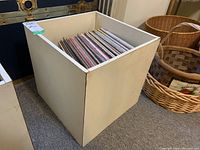White vinyl record storage bin filled with numerous albums, showing tops of album covers densely packed