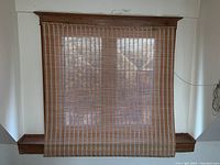 Full view of large rattan style blind with wood trim surrounding window frame