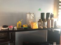 Wide shot on black table showing multiple candles, holders, decorative boxes including yellow boxes and small lanterns