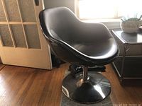 Front view of black faux leather swivel chair showing bucket-style seat and chrome pedestal base