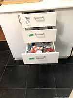 Three open drawers containing assorted cutlery and utensils