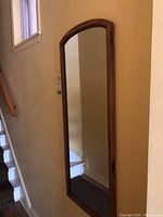 Full-length wall mirror mounted on wall by staircase. Pine frame with arched top visible.
