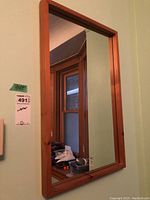 Photo showing entire mirror hanging on a wall with reflection of room including windows and household items.