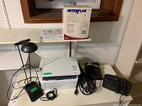Photo showing HP Laserjet Pro MFP M28w printer, Interplak 5000 oral care product boxed, Sony radio, Panasonic telephone, power cords and accessories on table.