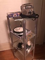 Full view of the radio, clocks, timer, and associated packaging on a four-tier metal stand
