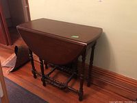 Wood table with drop leaf sides folded down, showing wear and wood grain finish.