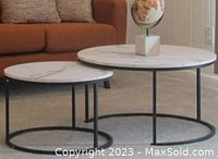 Photo showing two round coffee tables with white marble tops and black metal bases in a living room setting