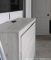Side and front angled view of the dresser depicting its light wood finish and drawer layout.