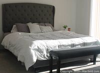 Grey queen size upholstered bed with tufted headboard, bedding and matching bench at foot of bed