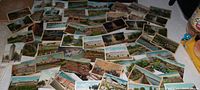 Wide spread of vintage postcards showing city and street scenes from various locations. Mostly colorful early 20th century lithographic prints.