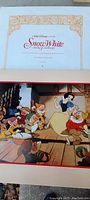 Snow White lithograph showing Snow White and the Seven Dwarfs in cottage setting, vibrant colors and animation style.