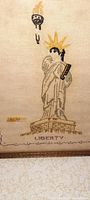 Close-up image showing the detailed embroidery of the Statue of Liberty including torch, crown, and pedestal with the word 'LIBERTY' stitched below.