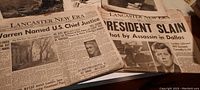Close-up photo of vintage newspapers including a Lancaster New Era paper with headline on President Kennedy assassination