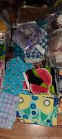 Mixed assortment of quilting fabric squares showing variety of colors and patterns including florals, plaid, and watermelon print