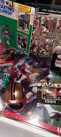 Overview showing 1991 National Series card sheet, Starting Lineup cards including Joe Montana, 1994 die-cast vehicle, and a miniature 49ers helmet on a football-themed display.