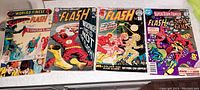 Four Flash-themed vintage comic books laid flat on a surface, showing clear cover art and titles.