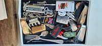 Top view of drawer containing approx. 20 various vintage items including small flatware, collectible lighters, playing cards, and other small collectibles.